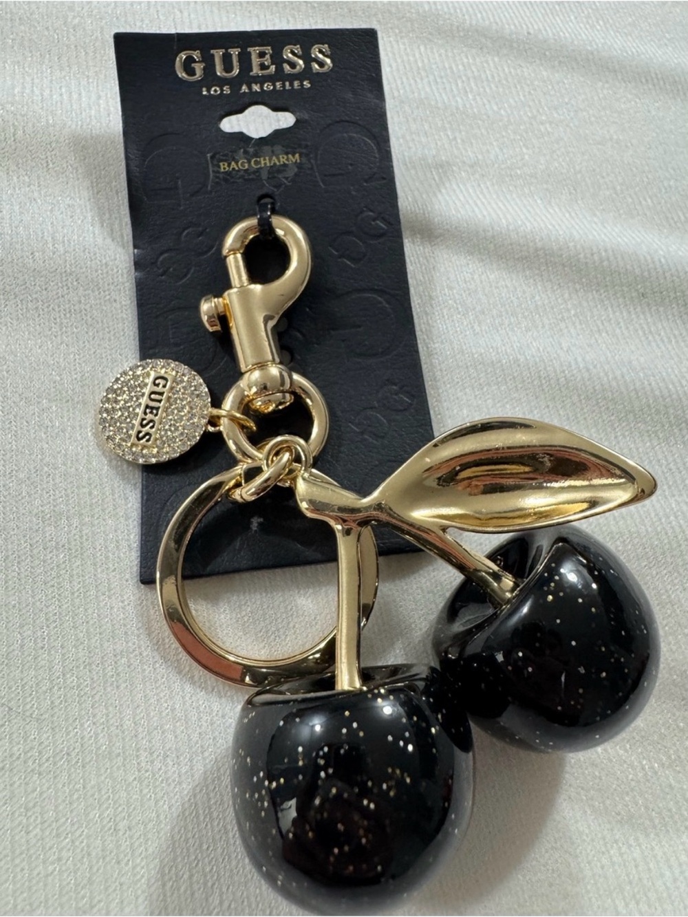 GUESS Black Glitter Cherry Bag Charm with Rhinestone Logo Disc in Gold Tone